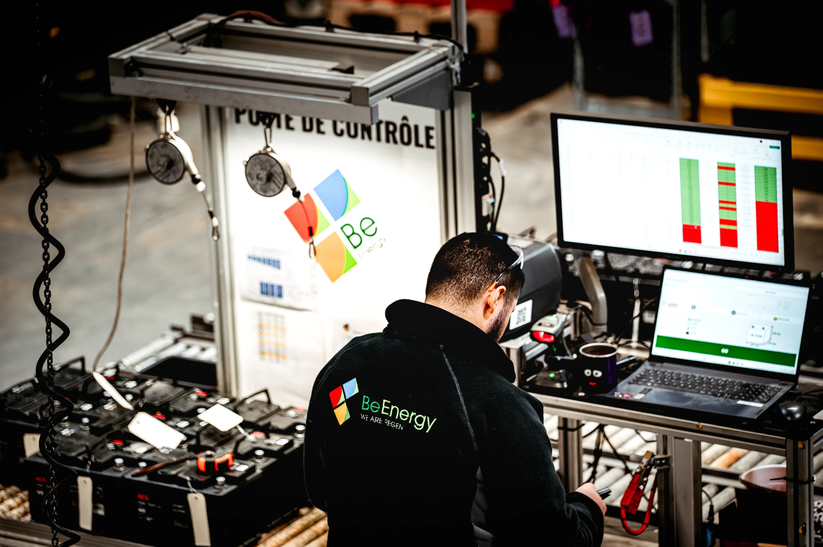 An operator using BeEnergy's Quick Tester Kiosk (QTK) to diagnose starter batteries on a production line.